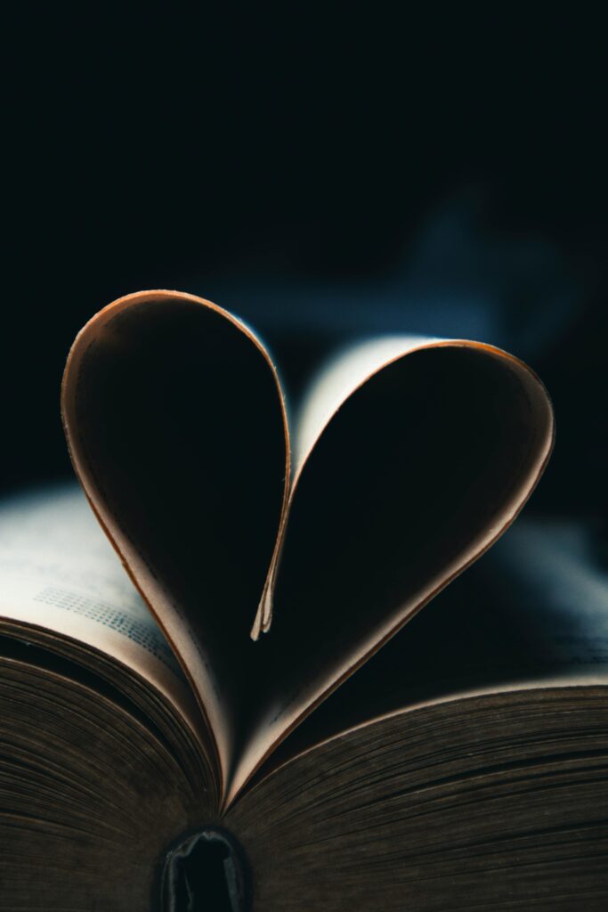 A book with pages forming a heart shape in dim, atmospheric lighting.